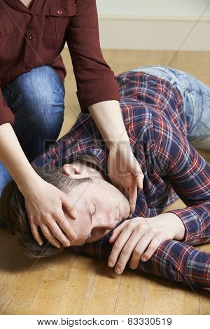 Woman Placing Man In Recovery Position After Accident