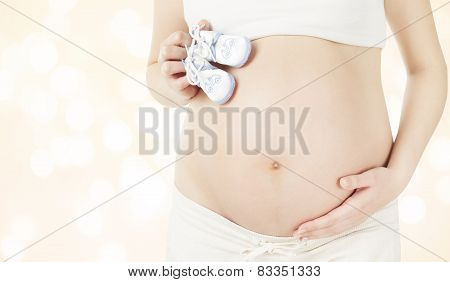Pregnant Stomach And Newborn Baby Booties, Woman Showing Belly And New Born Boots, Pregnancy Concept