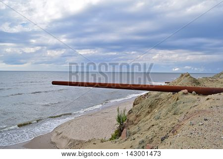 View big rusty pipe on the background of the sea in a beautiful nature
