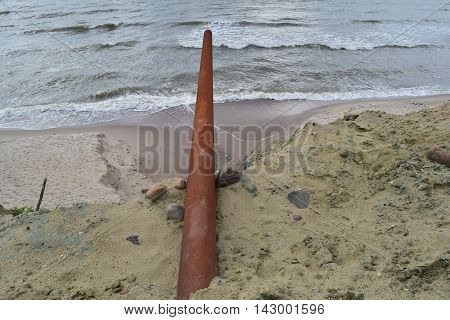 View big rusty pipe on the background of the sea in a beautiful nature