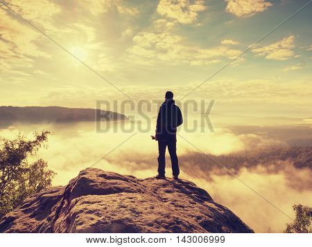 Professional Photographer With Tripod On Cliff And Thinking. Dreamy Fog