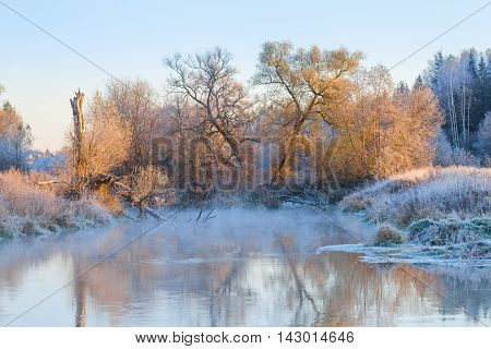 Winter landscape with a steaming river on frost and trees covered with hoar