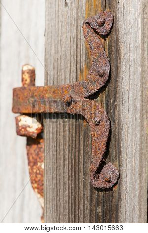 Vintage rusted metal door hinge over the weathered wooden wall.