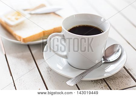 Coffee cup with bread on wooden table background.