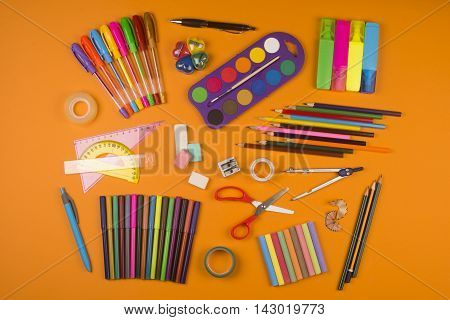 Different school supplies are on orange background.