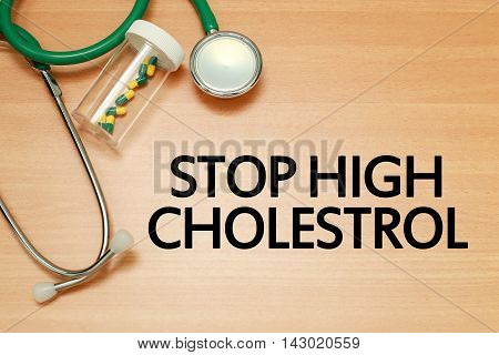 Medical concept - Stethoscope and pills on wood with Stop High Cholestrol word