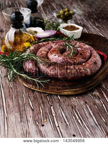 raw beef sausages on a cast-iron pan with rosemary and spices on a wooden table South African boerewors