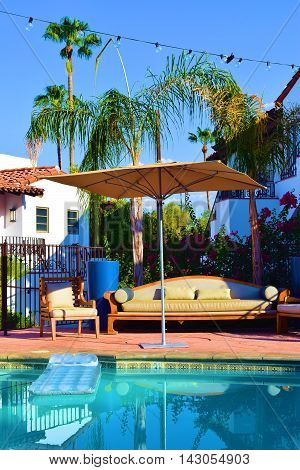 Floating raft in a pool surrounded with outdoor furniture and Palm Trees taken in a courtyard garden