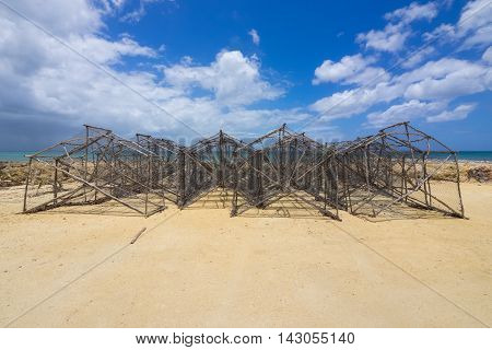 Hand made wooden pots ready for fishing are stacked on the beach in Guadeloupe