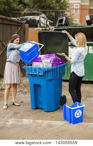 Young women fill single recycling container full.