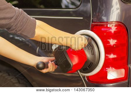 power buffer cleaning the tail lights of a car.