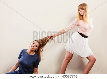 Aggressive mad women fighting each other pulling hair. Two young girls struggling win catfight. Violence.