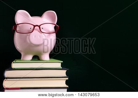 Piggy bank with glasses and blackboard copy space, back to school concept
