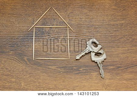 Keys and house symbol on a wooden background. Concept of a new home.