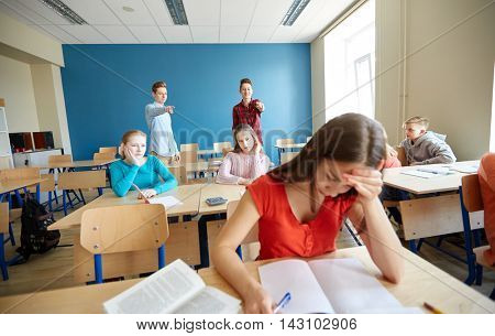 education, bullying, conflict, social relations and people concept - students teasing and judging girl classmate behind her back at school