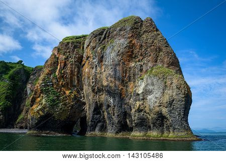 Green rocky cliffs form the coastline of the Avacha Bay, Kamchatka, Russia