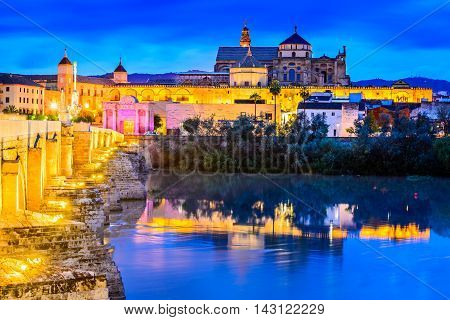 Cordoba Spain. Roman Bridge on Guadalquivir river and The Great Mosque (Mezquita Cathedral) at twilight in the city of Cordoba Andalusia.