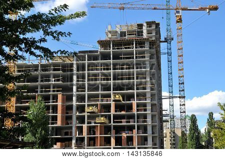 Working on place tall building under construction and cranes under a blue sky