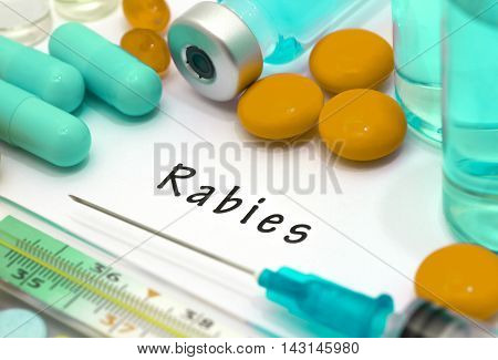 Rabies - diagnosis written on a white piece of paper. Syringe and vaccine with drugs.