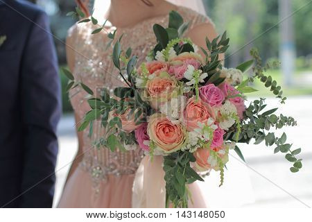 Bride holding a beautiful bridal bouquet. Wedding bouquet of peach roses by David Austin single-head pink rose aqua eucalyptus ruscus gypsophila