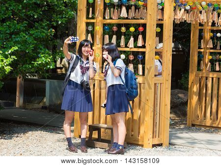 KAWAGOE JAPAN - 20 JULY 2016 - Female Japanese students use their smartphone to take their picture at Hikawa Shrine in Kawagoe Japan on July 20 2016.