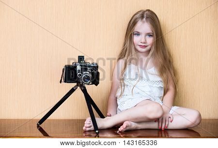 Little girl with oldest camera near wall