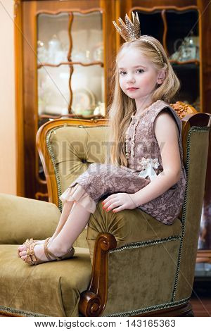 Little girl with crown on the chair