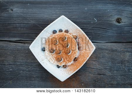 ice cream dessert decorated with berry fruit and cocoa powder on old grey wooden boards background