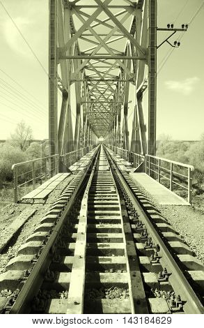 Old abandoned bridge on the river. Gray tones.