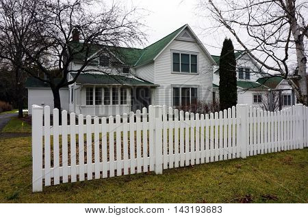 WEQUETONSING, MICHIGAN / UNITED STATES - DECEMBER 22, 2015: A white picket fence stands in front of a home on Pennsylvania Avenue in Wequetonsing.