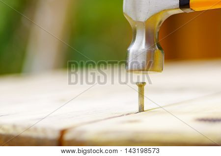 hammer smashing a nail in a piece of wood.