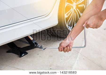 Hand lifting a car with spanner jack-screw