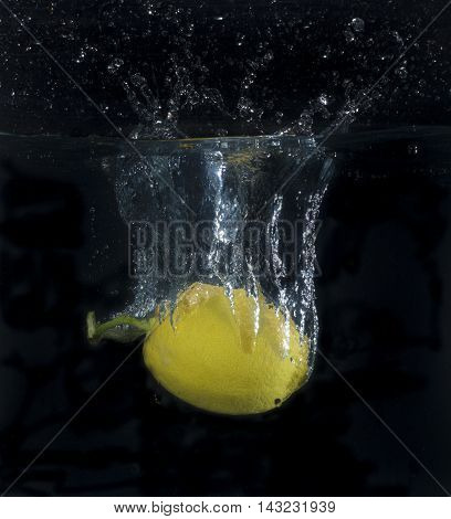 lemon dropped into water with bubbles and drops
