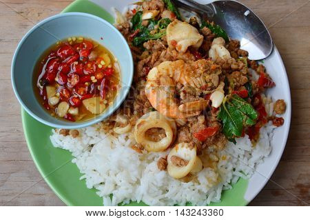 spicy stir-fried mixed seafood and minced pork with basil leaf on rice