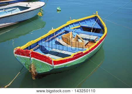 Malta - Colorful Mediterranean traditional Luzzu fishing boat at Marsaxlokk on a sunny summer day with green sea