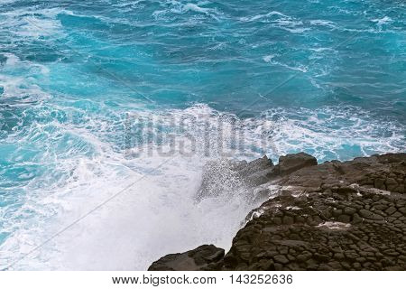 Deep blue sea water splashing volcanic rock at blowholes, rock tunnels, at Cape Bridgewater in Victoria, Australia