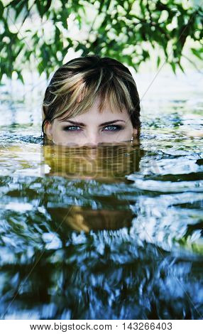 Young beautiful girl in a dark river water.