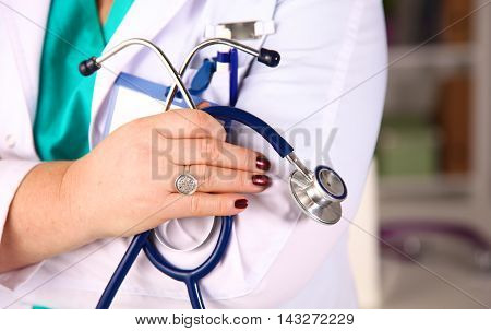 Beautiful general practitioner is working with joy. She is standing with a folder of documents in her hand.