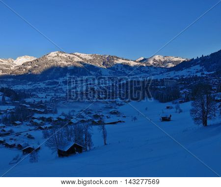 Sunrise on a beautiful winter morning in Gstaad. Famous village and travel destination in the Swiss Alps.