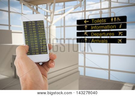 Male hand holding a smartphone against black airport departures board for australia