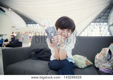 Beautiful Asian woman happy traveller waiting for flight travel at airport terminal