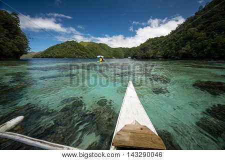 A canoe paddles over clear tropical water