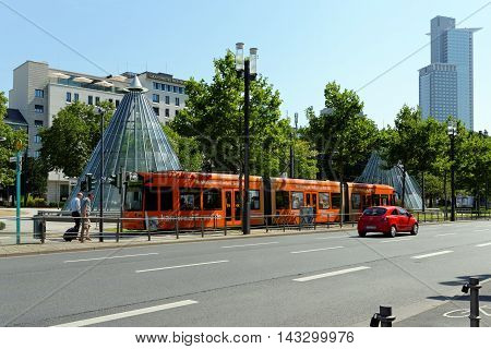 FRANKFURT AM MAIN GERMANY - AUGUST 7 2015: An electric tram near the Festhalle and Trade Fair tube station and the Westend Tower in the background.