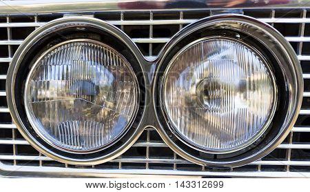 Detail of an attique car at a retro car parade. Two headlights. Headlamps.