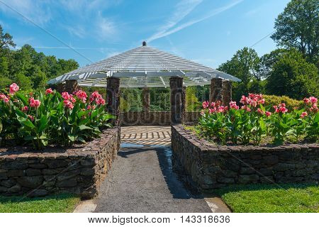 Gazebo surrounded by flowers and trees in a park under a blue sky