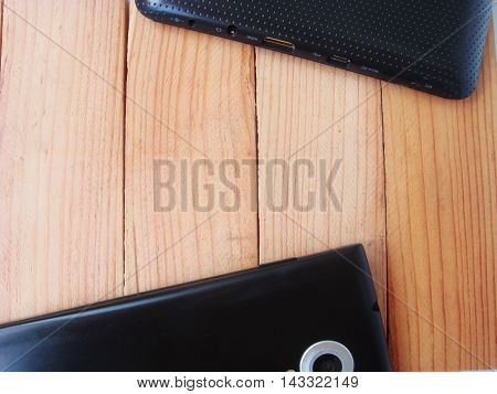 Background tablet and phone are on the table on a wooden substrate. In the middle there is a place for an advertising banner.