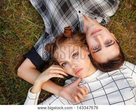 Sweethearts Teens lying on the grass head to head. Girlfriend and boyfriend together. First love. He falls in love. Date.