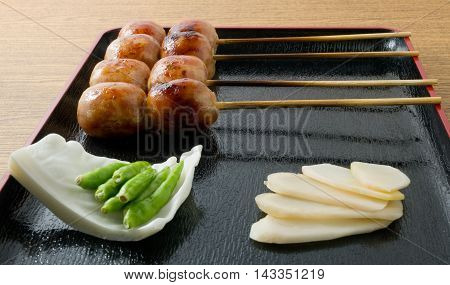 Food and Cuisine Plate of Thai Grilled Sausages on Wooden Skewer Served with Pickled Ginger Cabbage and Chili Pepper.