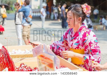 KAWAGOE JAPAN - 20 JULY 2016 - Japanese woman in yugata traditional japanese dress try her luck by baiting lucky fortune paper fish form the piles at Hikawa Shrine in Kawagoe town Japan on July 20 2016.
