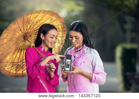 Portrait of Vietnamese girl traditional dress Ao dai is famous traditional costume for woman in Vietnam with vintage camera